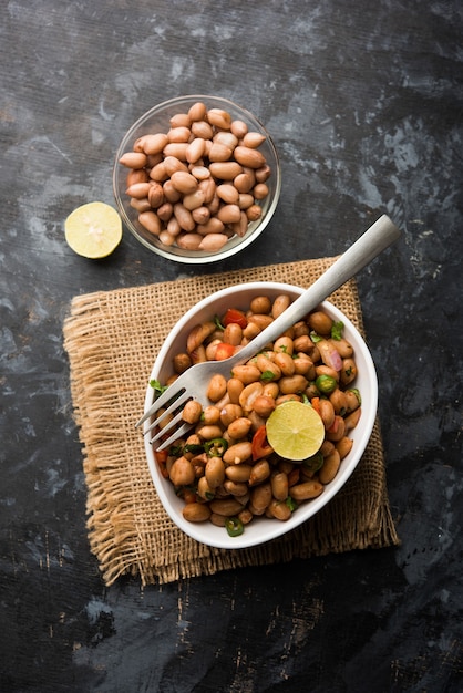 Boiled Peanut Chaat or Chatpata sing dana or shengdana or mungfali. served in a ceramic bowl over moody background