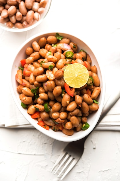 Boiled Peanut Chaat or Chatpata sing dana or shengdana or mungfali. served in a ceramic bowl over moody background