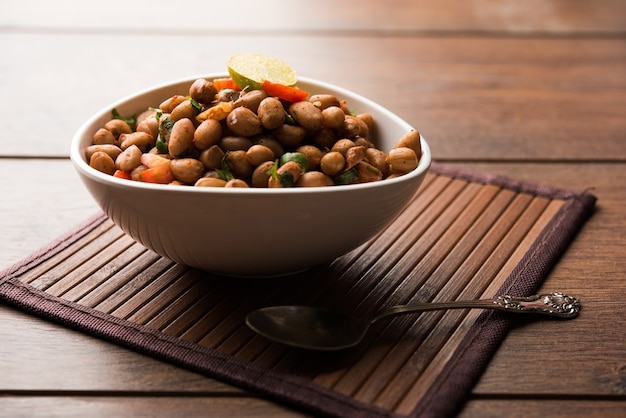 Boiled Peanut Chaat or Chatpata sing dana or shengdana or mungfali. served in a ceramic bowl over moody background