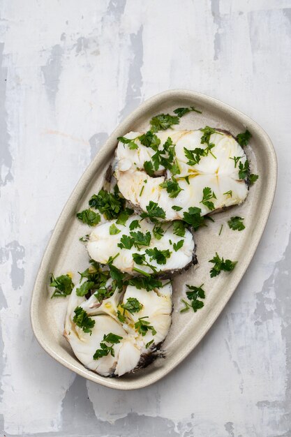 Boiled perch with parsley and olive oil on dish on ceramic surface