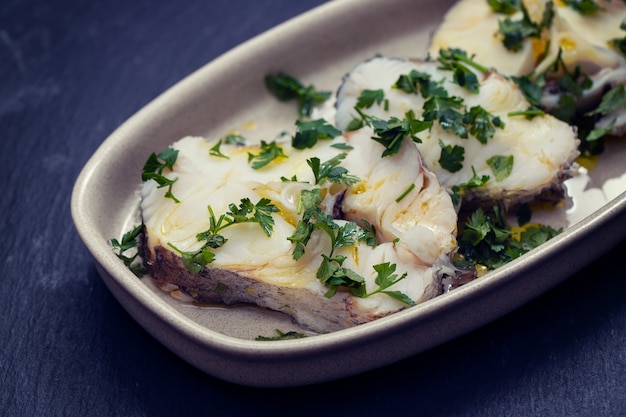 Boiled perch with parsley and olive oil on dish on ceramic surface