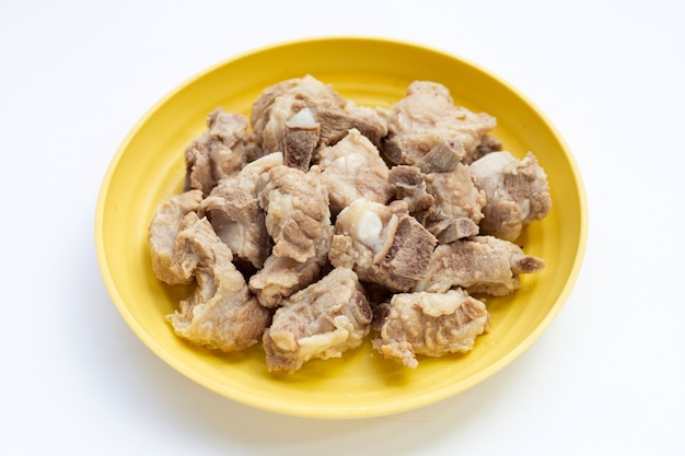 Boiled pork ribs in yellow plate on white background.