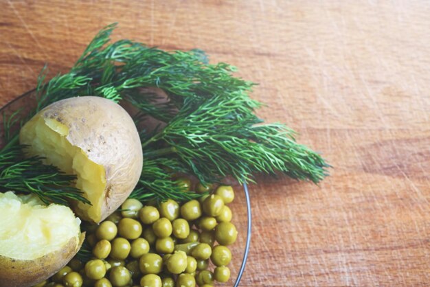 Boiled potatoes green peas and greens on a wooden Board