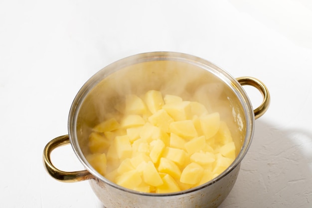 Boiled potatoes in a pot Hot potato cubes with a piece of butter Cooking boiled potatoes mashed potatoes Steam is coming White background