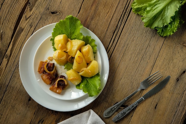 Boiled potatoes with cracklings homemade food and kitchen on a wooden table white utensils