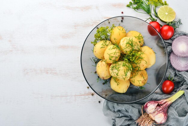 Foto patate bollite con aneto in una ciotola su uno sfondo di legno vista dall'alto copia spazio