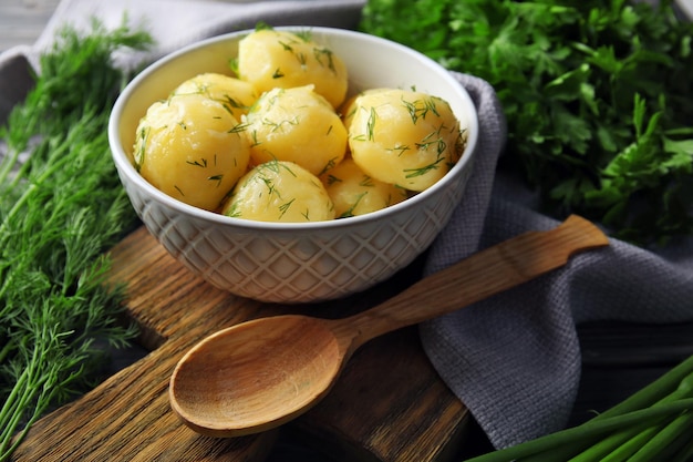 Boiled potatoes with greens in bowl on table close up