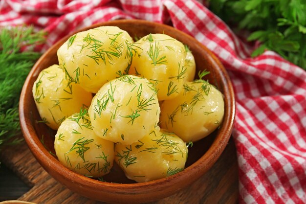 Boiled potatoes with greens in bowl on table close up