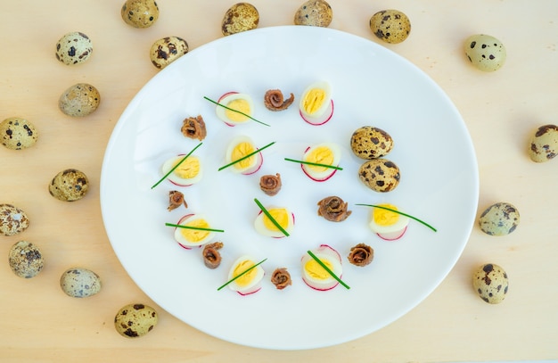 boiled quail eggs with anchovies and chives on a plate