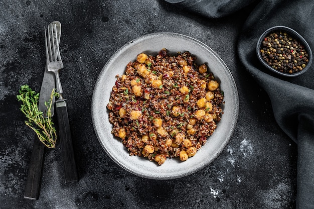 Boiled quinoa with chickpeas. Healthy food, diet on black. Top view