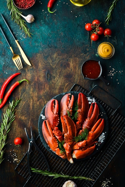 Boiled red lobster claws with spices and parsley on a black stone plate On a black background Rustic style Seafood delicacies