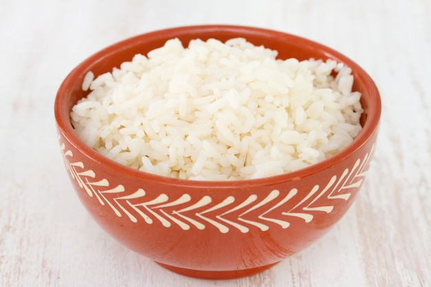Вареный рис в миску на белом фоне