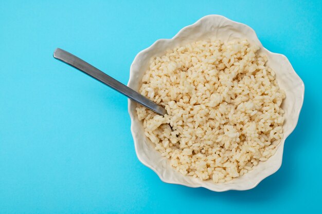 Boiled rice in white beautiful bowl with spoon