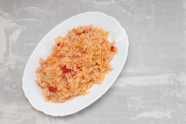 Boiled rice with tomato and spices on white dish