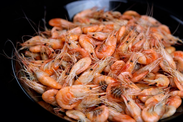 Boiled shrimp on a plate on black