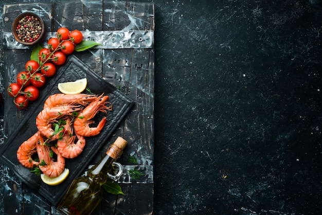 Boiled shrimp with parsley and lemon on a black stone plate Top view Seafood