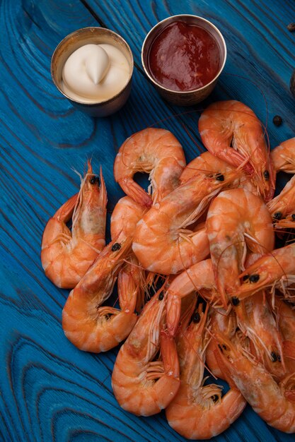 Boiled shrimp with pepper, salt and sauces on a wooden table