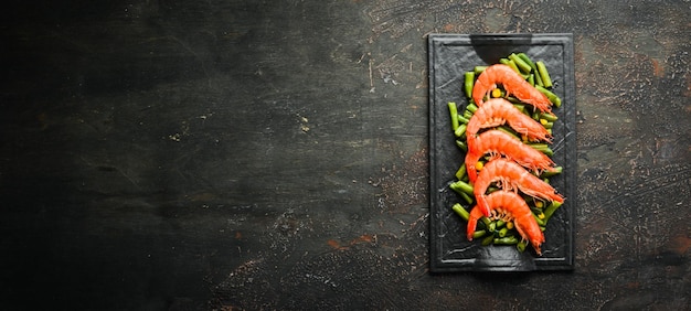 Boiled shrimps and green beans on a black stone plate Rustic style Top view Free space for your text