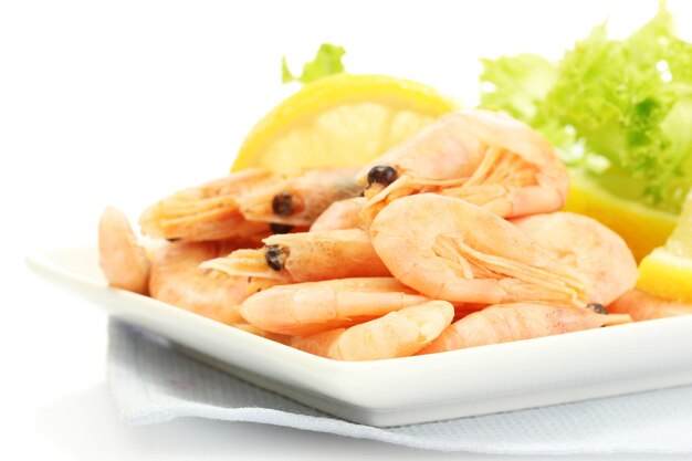 Boiled shrimps with lemon and lettuce leaves on plate isolated on white