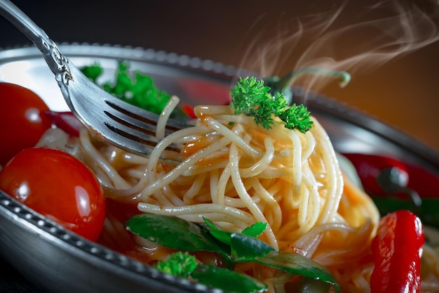 Boiled spaghetti with seasonings and vegetables on an old background