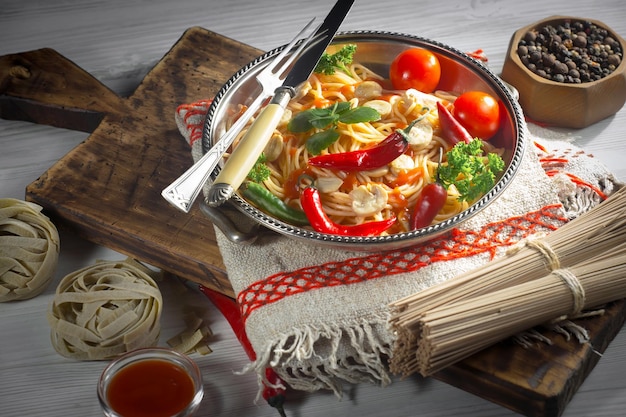 Photo boiled spaghetti with seasonings and vegetables on an old background