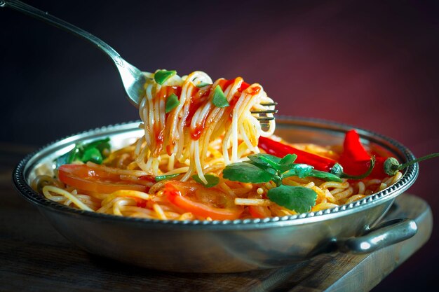 Boiled spaghetti with seasonings and vegetables on an old background