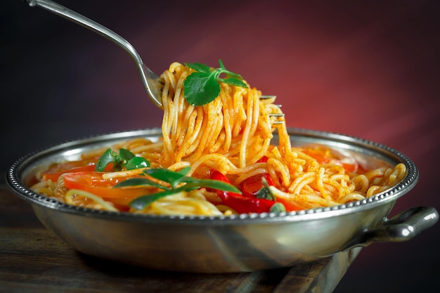 Boiled spaghetti with seasonings and vegetables on an old background