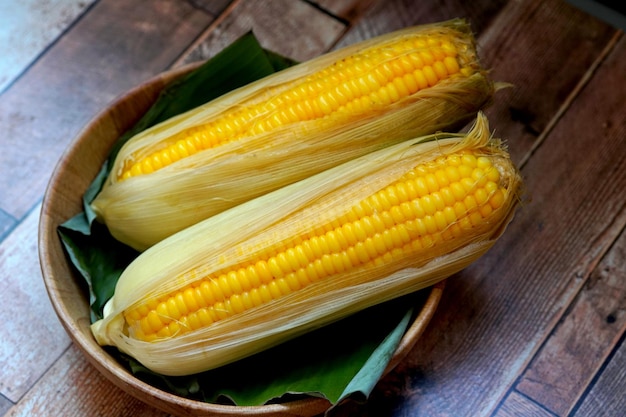 Boiled sweet corn in a bowl on wooden background