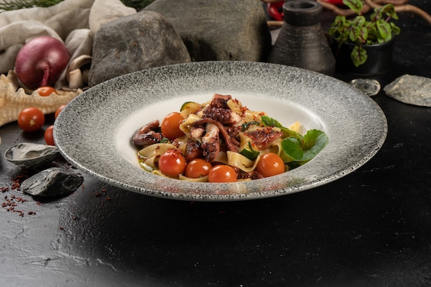 Boiled tagliatelle pasta with octopus and cherry tomatoes