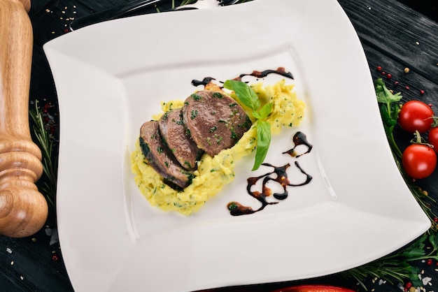 Boiled veal tongue with mashed potatoes on a plate On a wooden background Top view Copy space