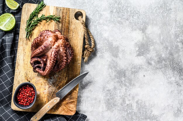 Boiled whole octopus on a cutting Board ready for cutting. Top view. Copy space