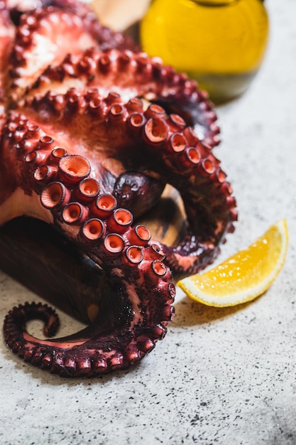 Photo boiled whole octopus on a gray stone with lemon and pink pepper