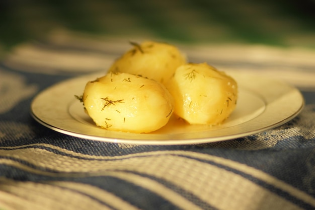 Boiled young potatoes with dill on a white plate Vegetarian food concept Closeup of potatoes on a blue napkin