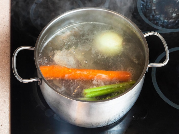 Boiling meat stock in stockpot on ceramic cooker