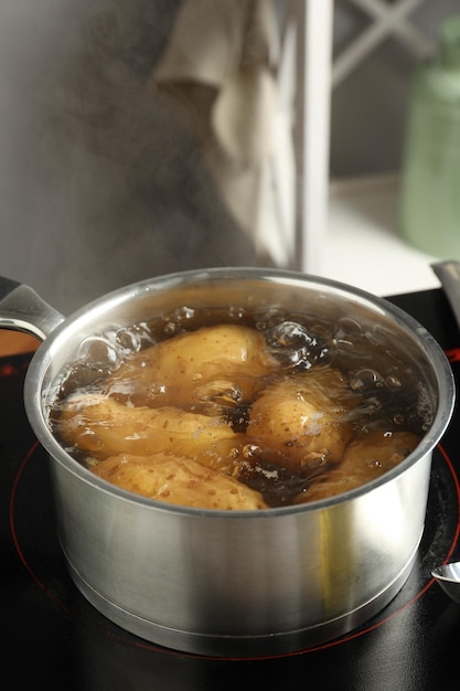 Кипящие картофель в кастрюле на плите на кухне