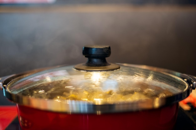 Zuppa bollente in pentola rossa con fumo sul tavolo