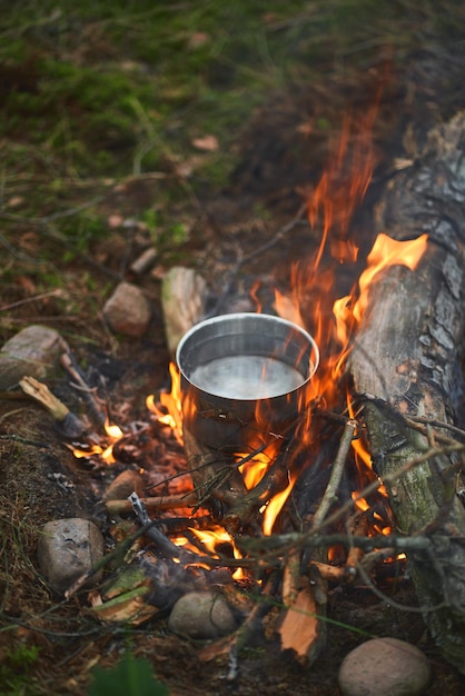 Boiling water at the camp fire concept of cooking food during\
night stay in the camp summer adventures in the woods