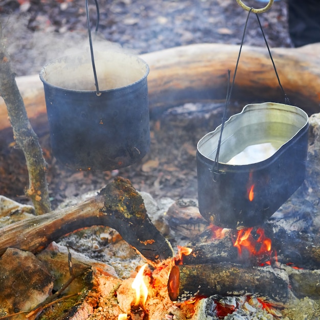 Boiling water in two pots above the fire.