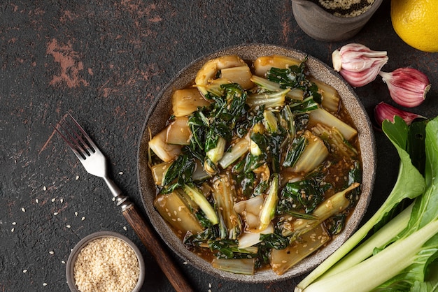 Photo bok choy vegetables stir fry with soy sauce and sesame seeds on dark background. chinese cuisine. top view