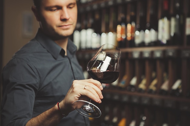 Bokal of red wine on background male sommelier appreciating drink