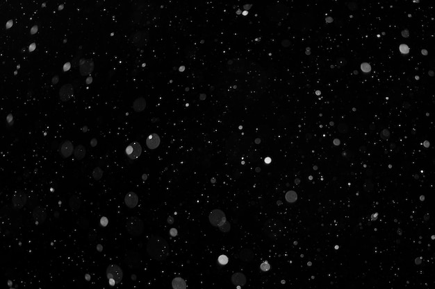 Un bokeh di neve bianca su sfondo nero