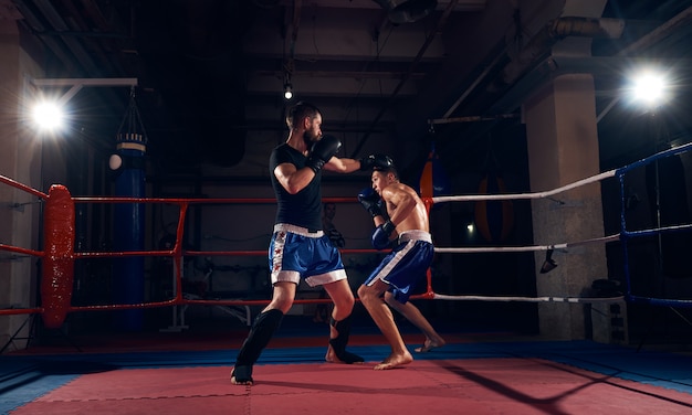 Boksers trainen kickboksen in de ring bij de healthclub