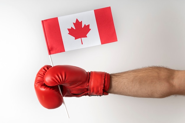 Bokshandschoen met vlag van Canada. Boxer houdt de vlag van Canada vast. Witte achtergrond.