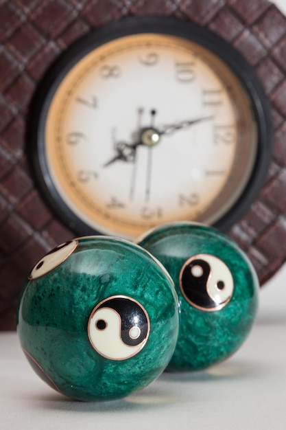 Bolas con dibujo del ying y el yang y reloj al fondo