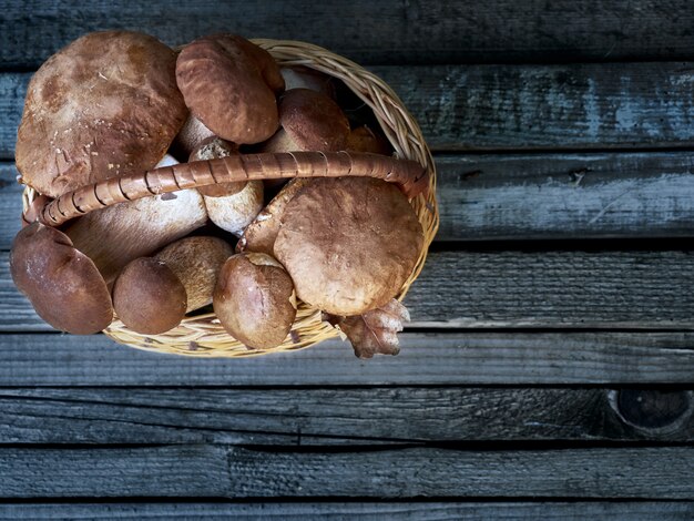 Foto il boletus si espande rapidamente in un canestro su un fondo di legno.