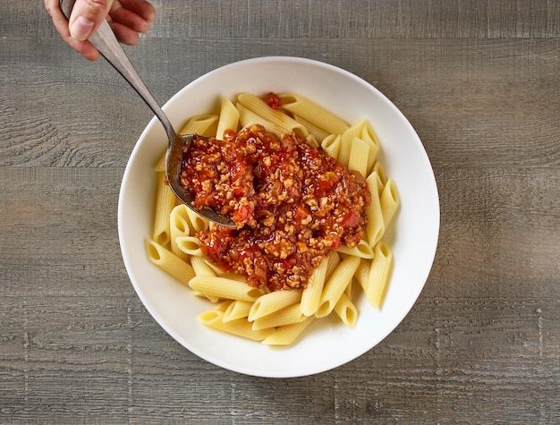 Photo bologna sauce is added to a bowl of pasta