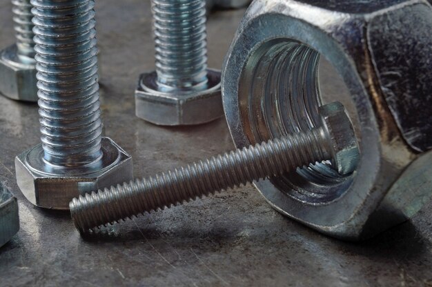 Bolts and hex nuts of various sizes, laid out on a metal surface. assorted closeups.