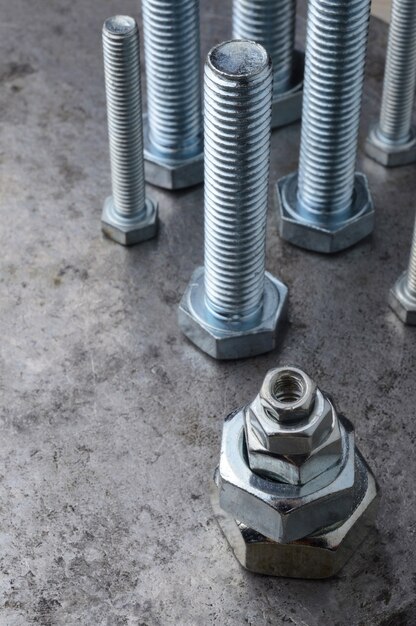 Bolts and hex nuts of various sizes, laid out on a metal surface. assorted closeups.