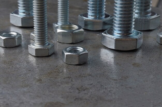 Bolts and hex nuts of various sizes, laid out on a metal surface