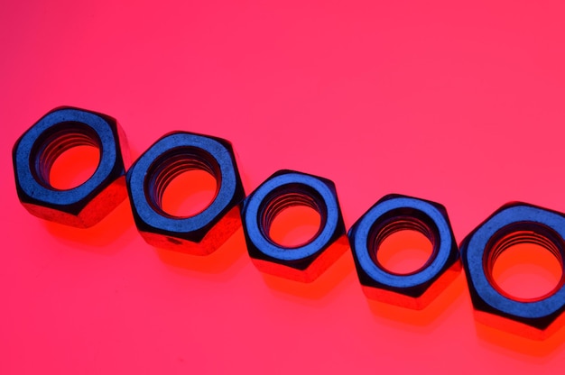 Bolts and nuts of different sizes on a red backgroundCloseup